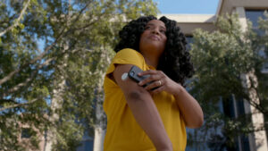 A woman scans a continuous glucose monitor with her smartphone