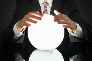 Close-up Of Businessman Predicting Future With Crystal Ball At Desk